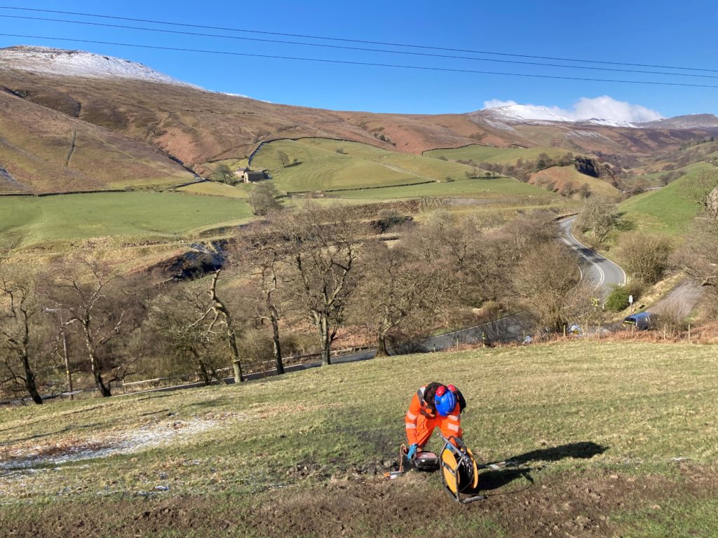 Manual monitoring using an inclinometer on Snake Pass in the Peak District to measure ground movement on a hillside.